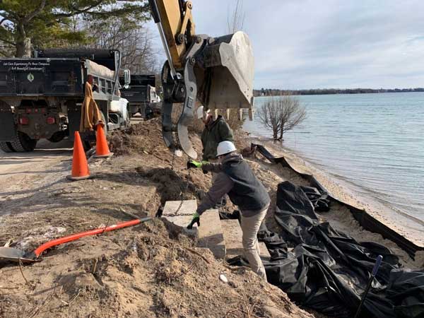 landscape installation crew works at shoreline with equipment