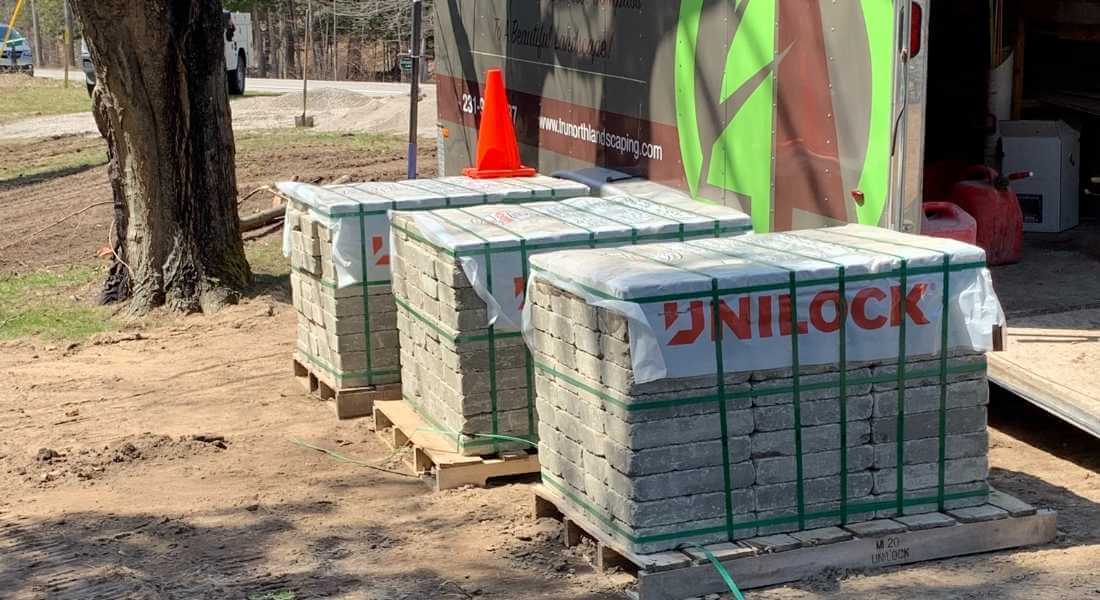 palettes of unilock stone infront of trunorth landscaping trailer