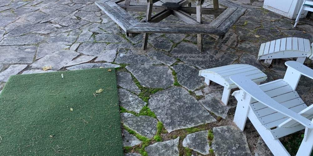 flagstone paver patio with uneven pavers and weeds growing through joints