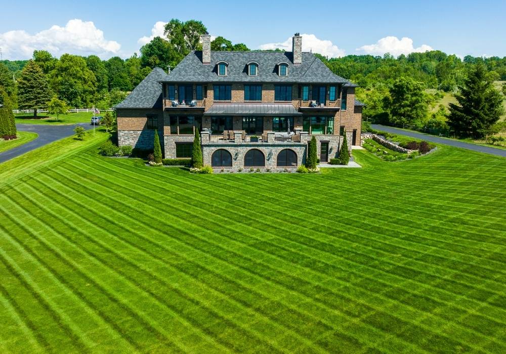 green grass with fresh mowing lines in front yard of large home