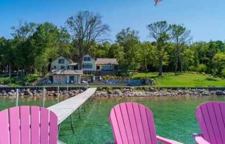 pink chairs on dock with home and landscape in background