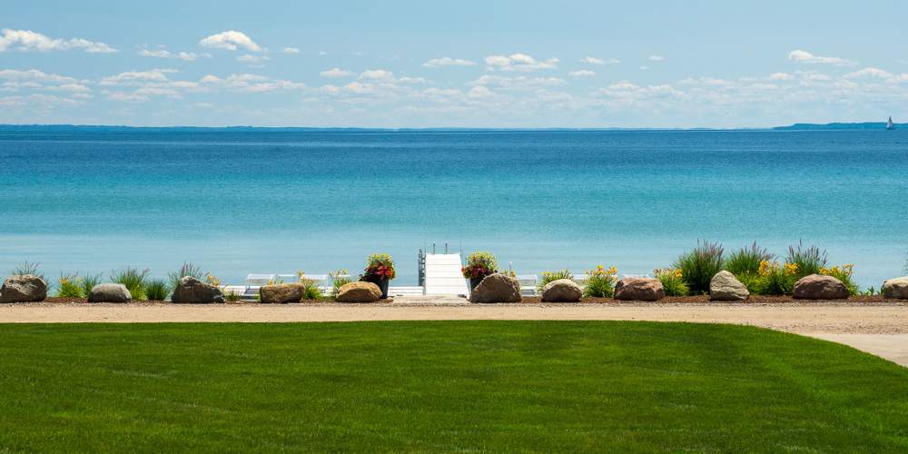 grass with plantings and beach overlooking water