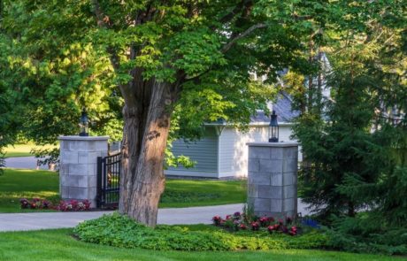 tree near pillars gate and unilock paver driveway