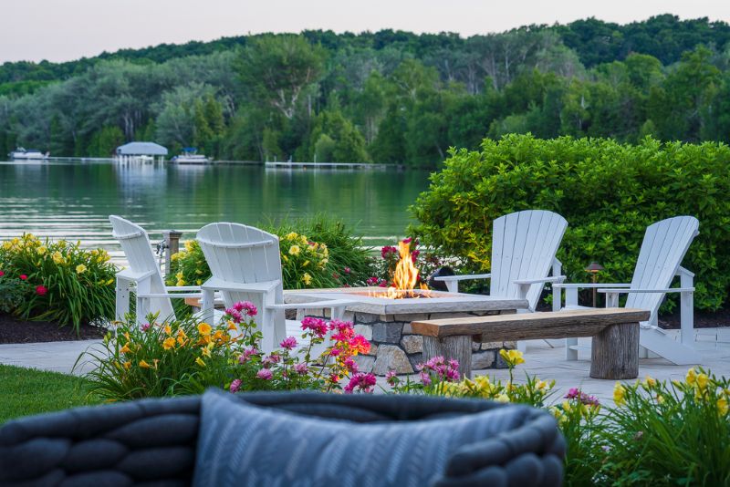 firepit on patio with chairs looking over lake